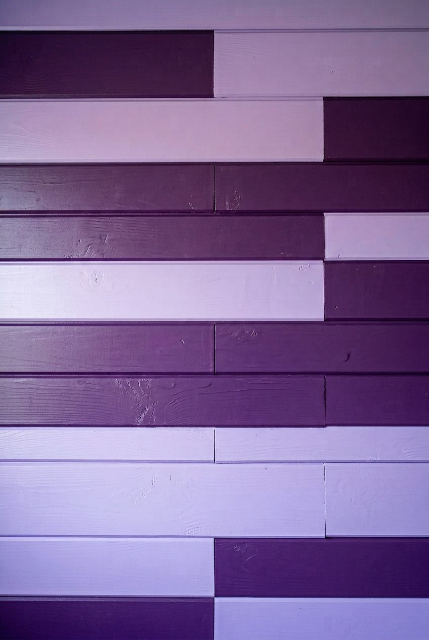Interior camper wall with staggered horizontal wooden panels painted in deep purple and lavender colors.